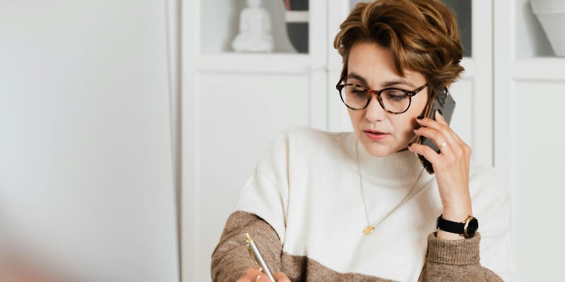 Modern businesswoman in casual outfit talking on mobile in office